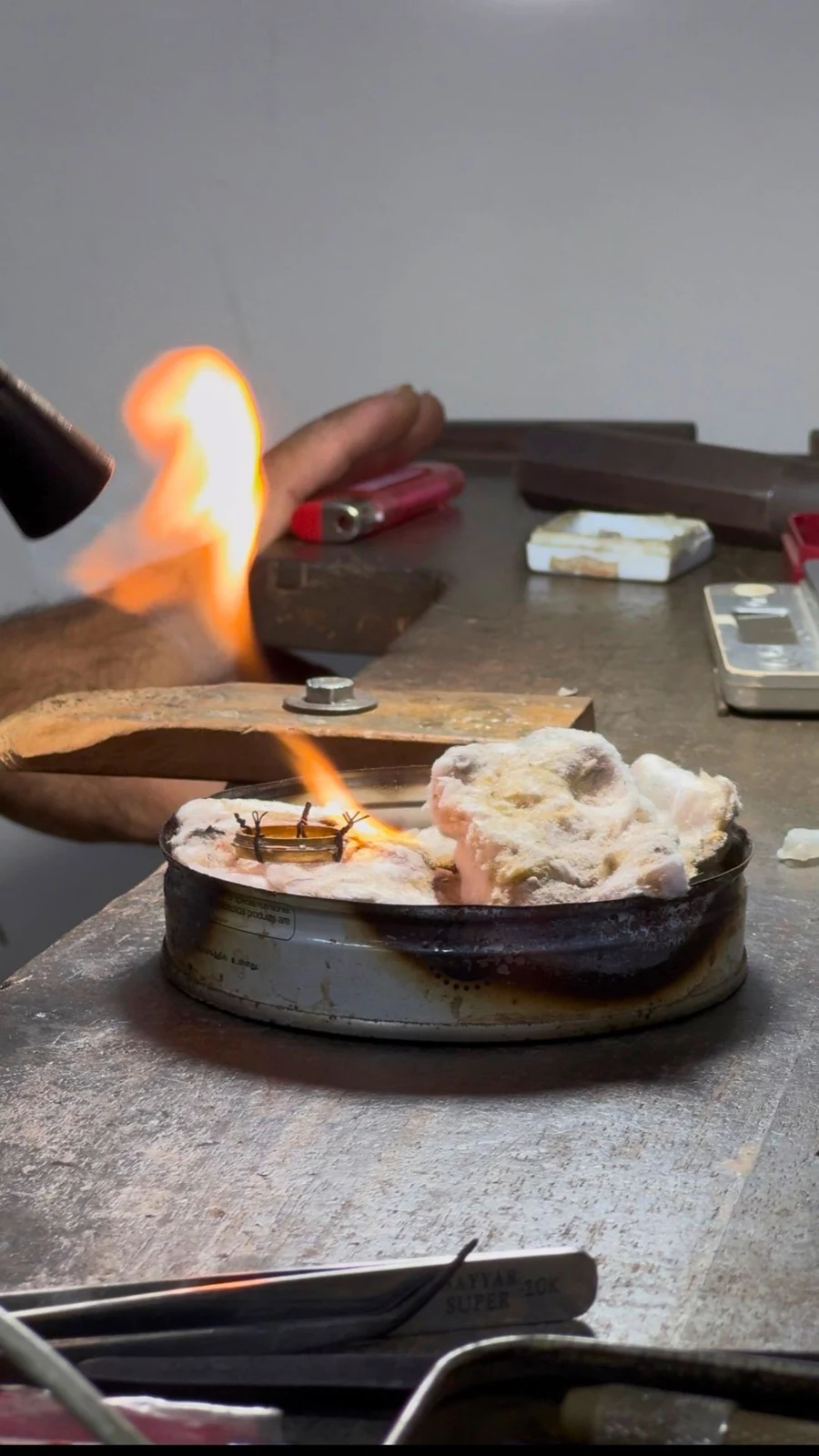 A flame heating metal on a workbench